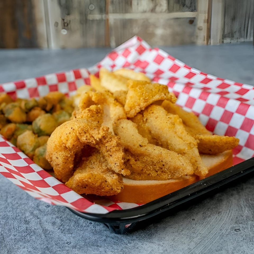 Fried catfish, french fries, and fried okra in a red and white checkered basket.