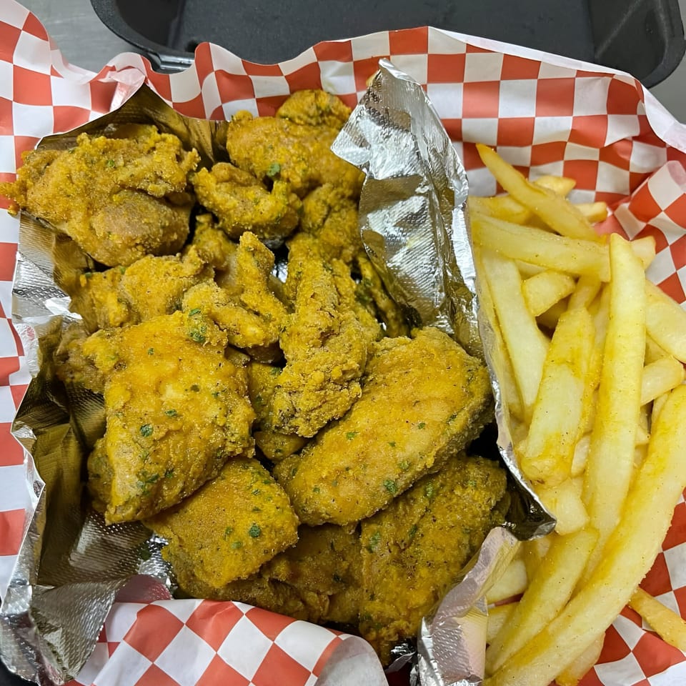 Golden fried fish nuggets and french fries in a red and white checkered paper container.