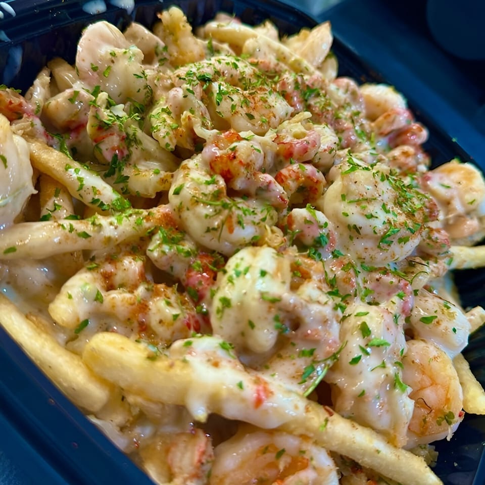 Close-up of Big Fish Bar and Grill's creamy shrimp and crawfish fries, topped with parsley.