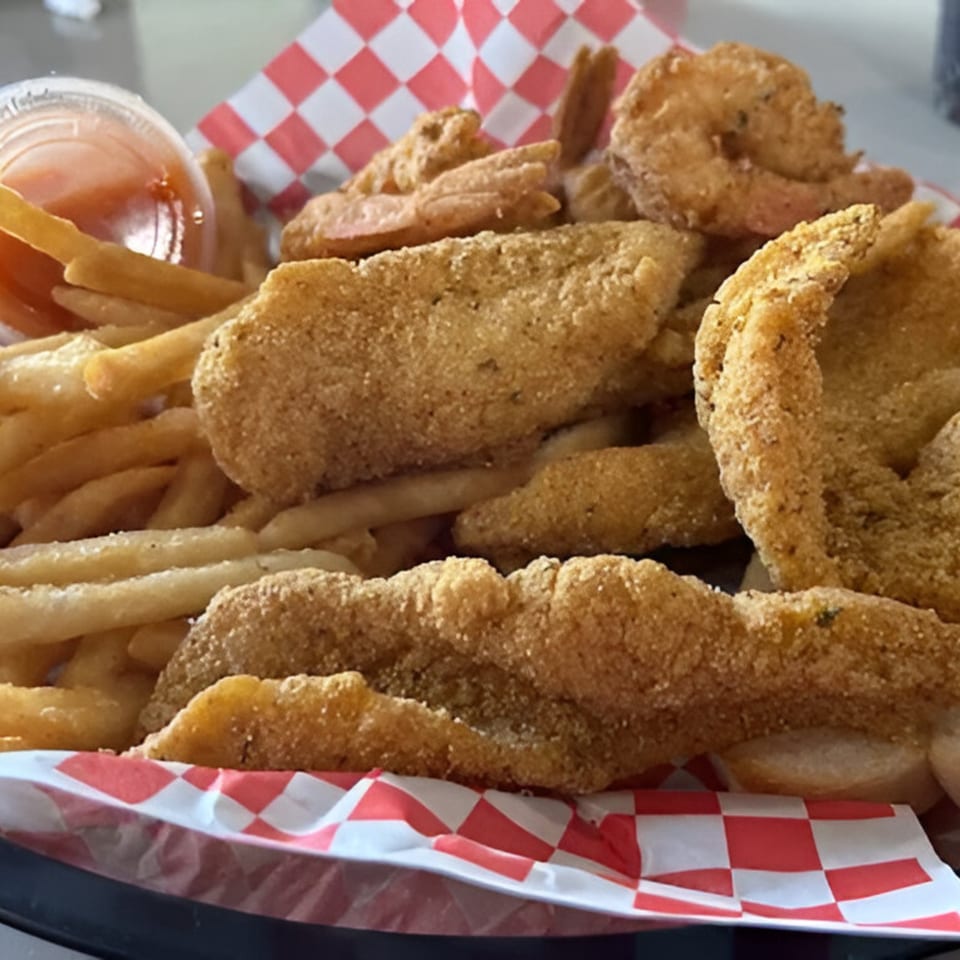 A basket of Big Fish Bar and Grill's fried shrimp and fish with french fries and dipping sauce.